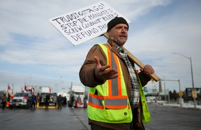 A person holds a sign while vehicles block the route leading from the Ambassador Bridge, linking Detroit and Windsor in a protest against the coronavirus vaccine mandates in Windsor today.