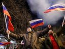 Prorussische Aktivisten feiern auf einer Straße, während ein Feuerwerk am Himmel explodiert, nachdem der russische Präsident Wladimir Putin am Montag ein Dekret unterzeichnet hatte, das zwei von Russland unterstützte abtrünnige Regionen in der Ostukraine als unabhängige Einheiten anerkennt.