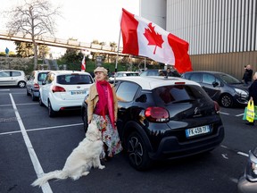 A woman and her dog stand by a Canadian flag before the start of their 'Convoi de la liberte' in Nice, France.