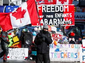 A protester waves a Canadian flag in front of banners in support of truckers in Ottawa on Monday.