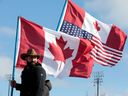 Ein Demonstrant trägt kanadische und amerikanische Flaggen, während er am 12. Februar 2022 den Eingang zur Ambassador Bridge in Windsor, Ontario, blockiert.
