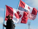 A protester carries Canadian and American flags while blocking the entrance to the Ambassador Bridge in Windsor, Ontario, on February 12, 2022.