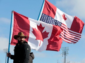 A protester carries Canadian and American flags while blocking the entrance to the Ambassador Bridge in Windsor, Ontario, on February 12, 2022.