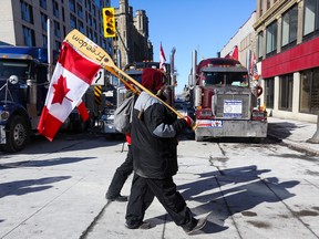 People carry canoe paddles with Canadian flags, as truckers and supporters continue to protest in Ottawa, on Monday.