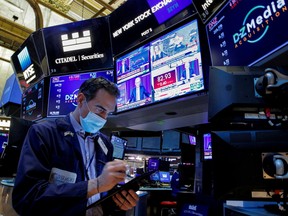 A trader works, as Federal Reserve Chair Jerome Powell is seen delivering remarks on screens, on the floor of the New York Stock Exchange (NYSE) in New York City, US, January 26, 2022.