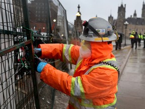 Arbeiter errichten einen Absperrzaun um das Parlamentsgebäude, während eine von Lastwagenfahrern organisierte Demonstration gegen Impfvorschriften am 17. Februar 2022 in Ottawa fortgesetzt wird.