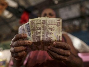 Ein Verkäufer zeigt auf einem Gemüsegroßmarkt in Mumbai, Indien, fünfhundert, einhundertfünfzig indische Rupie-Banknoten zum Fotografieren an.