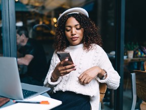 Pensive dark skinned millennial hipster girl watching videos browsed web page on smartphone, beautiful thinkign african american woman freelancer using banking app for paying and transaction online