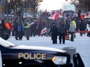 Police keep watch as demonstrators participating in a protest organized by truck drivers opposing vaccine mandates continue to gather on the streets in Ottawa on Feb. 19, 2022.