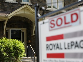 A realtor's for sale sign stands outside a house that has been sold in Toronto.