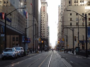 Pedestrians cross the intersection at Bay Street and Wellington Street West in the financial district of Toronto.