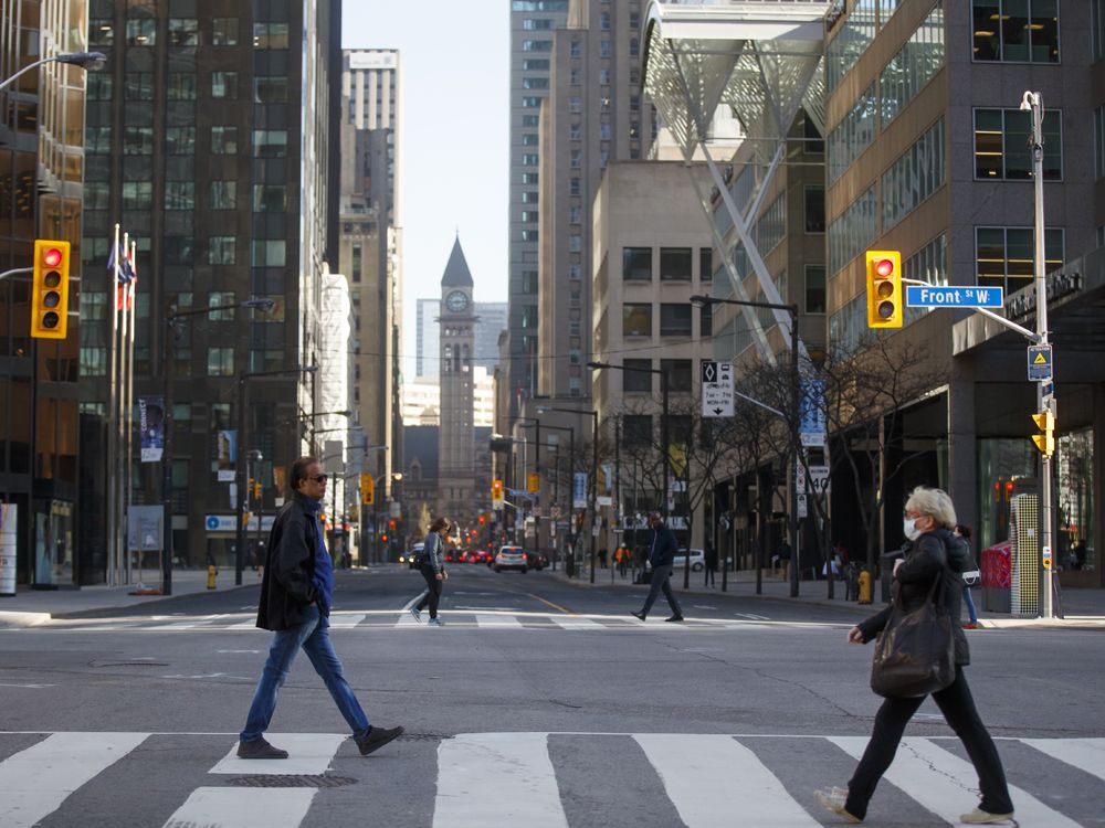 morning commuters cross yonge street at bay street in the financial district of toronto.