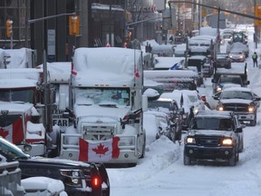 Vehicles drive by trucks participating in a blockade by truck drivers opposing vaccine mandates near Parliament Hill on Feb. 18, 2022 in Ottawa.