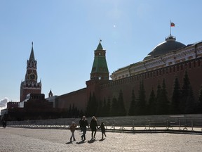 People walk in Red Square near the Kremlin Wall in central Moscow, Russia.