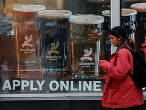 A sign advertising available jobs at the Clocktower Brew Pub hangs in a window in Ottawa.