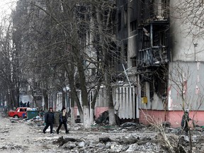Local residents walk near a residential building which was damaged during the Ukraine-Russia conflict in the besieged southern port city of Mariupol, Ukraine on March 18, 2022.