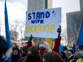 A woman holds a sign as members of the Ukrainian community protest at Place du Canada in Montreal, Que.