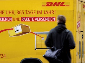 Ein Mann fährt in Berlin an einem DHL-Lkw vorbei.