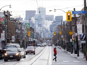 A pedestrian wearing a protective mask crosses a street in Toronto.