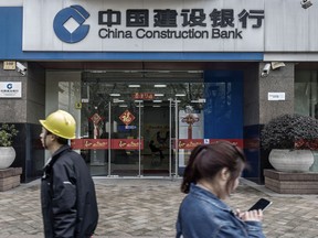 Pedestrians walk past a China Construction Bank Corp. branch in Shanghai, China.