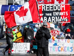 A person waves a Canadian flag in front of banners in support of truckers in Ottawa, on Feb. 14, 2022.
