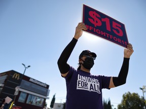 A man holds up a minimum wage sign at a rally held by fast food workers and supporters in Los Angeles, California.