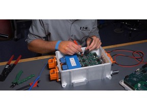 Eaton eMobility engineer inspects a high-voltage traction inverter for electric vehicles.