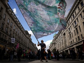 A man holds up a flag as climate activists from Extinction Rebellion take part in a demonstration at Oxford Circus in London, Britain, April 9, 2022.
