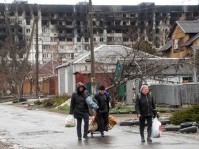 Local residents walk in front of a residential building damaged in the course of Ukraine-Russia conflict, on a rainy day in the southern port city of Mariupol, Ukraine, on April 13, 2022.
