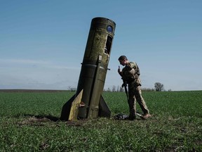 A Ukrainian serviceman looks at a Russian ballistic missile's booster stage that fell in a field in Bohodarove, eastern Ukraine, on April 25, 2022.