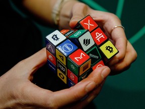 An attendee plays with a puzzle cube displaying logos of different cryptocurrencies and exchanges at the CryptoCompare Digital Asset Summit at Old Billingsgate in London, U.K., on Wednesday, March 30, 2022.