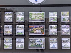 Real estate listings displayed on a brokerage window in Toronto.