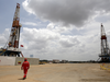 An oilfield worker walks next to drilling rigs at an oil well operated by Venezuela's state oil company PDVSA.