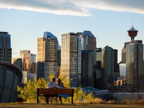 Ein junges Paar teilt einen romantischen Moment, kurz bevor die Sonne hinter der Skyline von Calgary untergeht.
