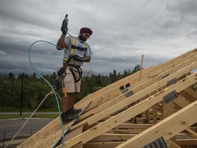 Ein Arbeiter nagelt Sperrholz auf das Dach eines im Bau befindlichen Hauses in Edmonton.