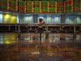 A man sits before electronic boards showing stock movements at the Malaysia Stock Exchange in Kuala Lumpur.