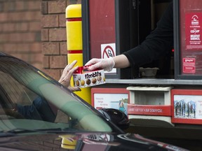 A Tim Hortons employee hands out timbits from a drive-through window to a customer in Mississauga, Ont.