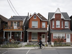 A cyclist rides past a row of houses in Toronto.