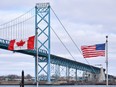 Canadian and American flags fly near the Ambassador Bridge at the Canada-U.S. border crossing in Windsor, Ont.