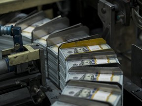 Stacks of money move through a machine during the production of new US$100 bills.