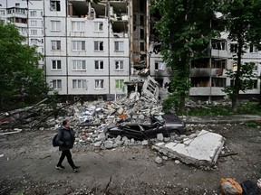 A woman walks past a heavily damaged residential building in the Saltivka district, northern Kharkiv on May 29, 2022, amid the Russian invasion of Ukraine.