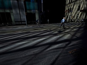 A businessman runs across Bay Street in Toronto's financial district as the morning light sweeps across the street on Thursday, June 14, 2012.