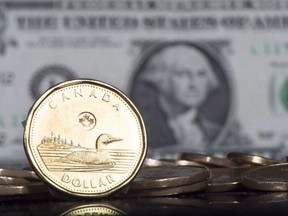 The Canadian dollar coin, the Loonie, is displayed next to the US dollar Friday, January 30, 2015 in Montreal.