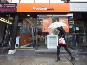 A woman walks past a Freedom Mobile store in Toronto, Thursday, Nov. 24, 2016. Rogers Communications Inc. says it will sell Freedom Mobile Inc. to Quebecor Inc. for $2.85 billion in a deal it hopes will appease the concerns of federal regulators about its proposed takeover of Shaw Communications.&ampnbsp;THE CANADIAN PRESS/Nathan Denette