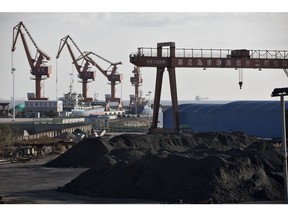 Piles of coal sit near port facilities as gantry cranes stand in the background at the Qinhuangdao Port in Qinhuangdao, China, on Friday, Oct. 28, 2016. China's efforts to quell surging coal prices showed signs they're working, with benchmark prices dropping for the first time in a year as the country's production rose to the highest in seven months. Photographer: Qilai Shen/Bloomberg
