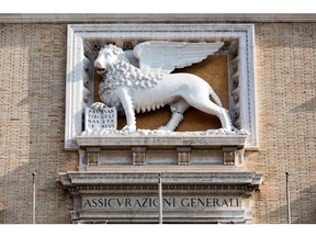 A sign sits below a Lion of St. Mark statue on a wall of the headquarters of Assicurazioni Generali SpA in Rome, Italy, on Friday, Jan. 27, 2017. Intesa Sanpaolo SpA Chief Executive Officer Carlo Messina, whose bank is considering a merger with insurer Assicurazioni Generali SpA, vowed to defend Italy's national interest.