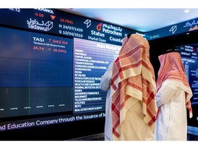 Visitors look at stock price information displayed on a digital screen inside the Saudi Stock Exchange, also known as the Tadawul, in Riyadh, Saudi Arabia, on Tuesday, April 10, 2018. Foreign investors bought more Saudi stocks in March than ever before in anticipation of the kingdom's upgrade to emerging-market status. Photographer: Abdulrahman Abdullah/Bloomberg
