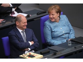 Olaf Scholz, Germany's finance minister, left, reacts as he sits beside Angela Merkel, Germany's chancellor, during a budget policy plan speech in the lower-house of the Bundestag in Berlin, Germany, on Wednesday, May 16, 2018. Merkel said governments must step up efforts to integrate the euro area because the European Central Bank's expansive monetary policy won't last forever.