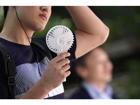 A man uses a Handy Fan as he walks in the Otemachi business district in Tokyo, Japan, on Monday, July 29, 2019.  Photographer: Toru Hanai/Bloomberg