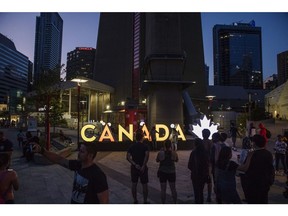 Visitors gather near an illuminated Canada sign outside the CN Tower in Toronto, Ontario, Canada, on Sunday, Aug. 4, 2019. Canada is scheduled to release gross domestic product (GDP) figures on August 30. Photographer: Brent Lewin/Bloomberg